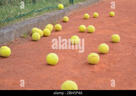 Gelbe Tennisbälle liegen nach dem individuellen Coaching auf dem orangefarbenen Sandplatz Stockfoto