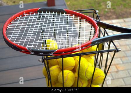 Tennisschläger mit vielen gelben Kugeln im Korb bereit für Coaching und Spiel Stockfoto