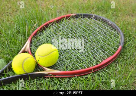 Tennisschläger und gelbe Bälle liegen auf dem Gras, bereit für Training und Spiele Stockfoto