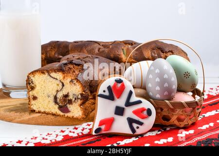 Scheiben von rumänischen Biskuit mit roten traditionellen Handtuch mit Handstich auf Holzbrett, Ostern bemalte Eier und hausgemachte Ingwer Brot Herzen, EIN Stockfoto