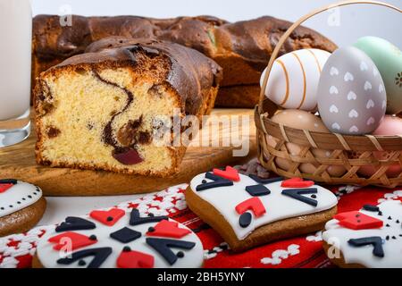 Scheiben von rumänischen Biskuit mit roten traditionellen Handtuch mit Handstich auf Holzbrett, Ostern bemalte Eier und hausgemachte Ingwer Brot Herzen, EIN Stockfoto