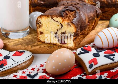 Scheiben von rumänischen Biskuit mit roten traditionellen Handtuch mit Handstich auf Holzbrett, Ostern bemalte Eier und hausgemachte Ingwer Brot Herzen, EIN Stockfoto