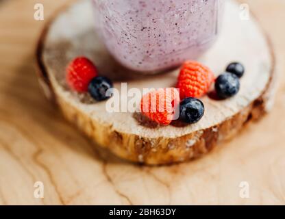 Gesunder Vitaminshake mit Drachenfrucht, Beeren, Chiasamen und Mandelmilch in einem stilvollen Glas, dekoriert mit Himbeere und Heidelbeere Stockfoto