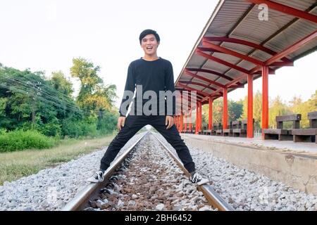 Ein Thai Boy steht auf der Bahn in den örtlichen Bahnhof. Stockfoto