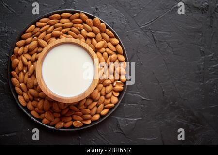 Zusammensetzung von Mandeln, Samen und Milch, auf schwarzem Steingrund. Stockfoto