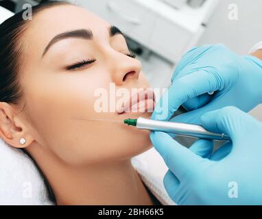 Frau verjüngt Gesicht mit kosmetischen Verfahren. Gesichtsspritzen machen die Haut glatt und jung. Makro Stockfoto