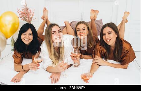 Vier Freundinnen mit Wein genießen Pyjamas Party zu Hause. Feiern Sie die Junggesellinnenabschied Stockfoto