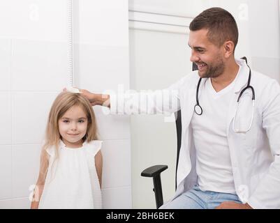 Der Arzt misst das Wachstum eines kleinen Mädchens. Kinderarzt und kleiner Patient Stockfoto
