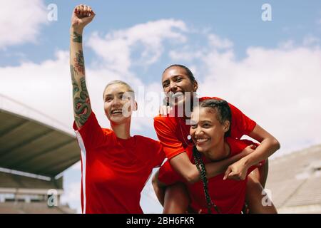 Begeisterte Fußballspielerinnen, die nach einem Tor feiern. Teamkollegen feiern den Sieg mit dem Torschützen. Stockfoto