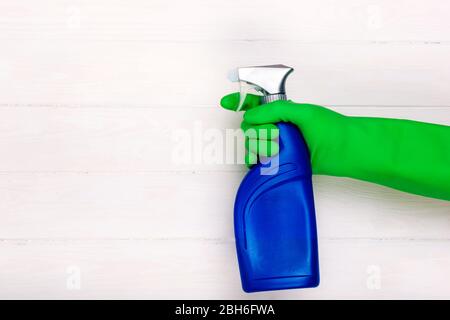 Hand mit Gummihandschuh halten Reinigungsspray , auf weißem Holzhintergrund Stockfoto