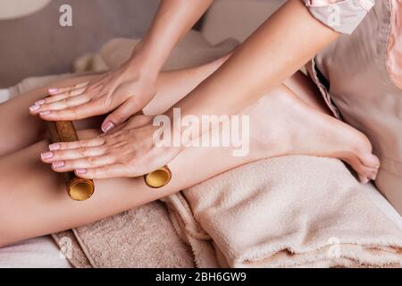 Massage des menschlichen Fußes im Spa-Salon mit Bambusstäbchen. Nahaufnahme der Füße, kaukasische Frau mit einem Massage-Spa-Salon Stockfoto