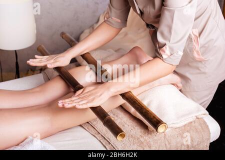 Frau mit Anti-Stress-Massage mit Bambusstäbchen. Spa Salon Verjüngende Körpermassage Stockfoto