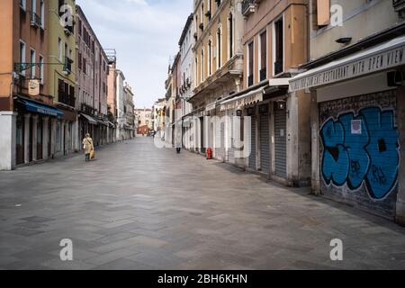 VENEDIG, ITALIEN - APRIL 2020: Menschen gehen während der nationalen Sperrung der Covid-19-Pandemie in einer leeren Straße. Stockfoto