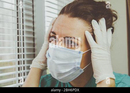 Ein Arzt in einer chirurgischen Schutzmaske sieht nach einer geschäftigen Schicht im Krankenhaus während einer Coronavirus-Epidemie erschöpft aus. Stockfoto