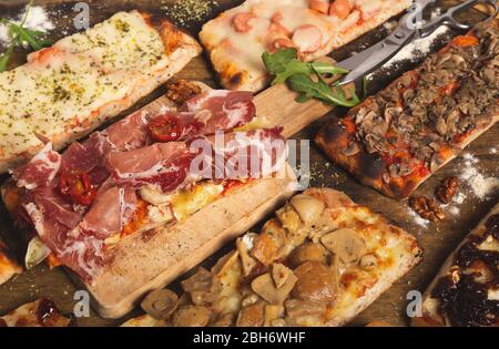 Nahaufnahme einer Auswahl an hausgemachten Pizzabschnitten. Rechteckige Portionen. Italienisches Essen. Auswahl an hausgemachten Pizzen. Stockfoto