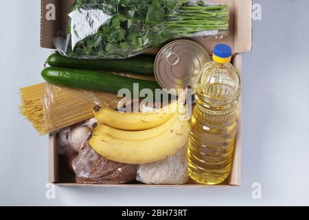 Box mit Lebensmitteln Krise Nahrungsmittelvorrat für Quarantäne Isolationszeit auf hellblauem Hintergrund. Reis, Buchweizen, Nudeln, Dosenfutter, Banane Stockfoto