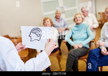 Sprecher mit einer Zeichnung des Gehirns erklärt Alzheimer-Krankheit zu den Senioren Stockfoto