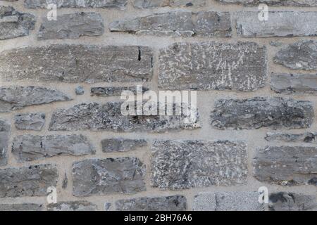 Strukturierte natürliche Tapete aus gehämmerten gemeißelten Granit Steinwand und Fugen Stockfoto