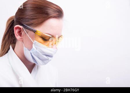 Nahaufnahme Profil Porträt einer Ärztin mit medizinischer Maske und gelber Schutzbrille. Konzept der Covid-19 Quarantäne mit leerem Raum für t Stockfoto