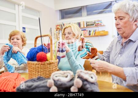 Gruppe alter Frauen, die in einer Handwerkswerkstatt im Altersheim häkeln Stockfoto