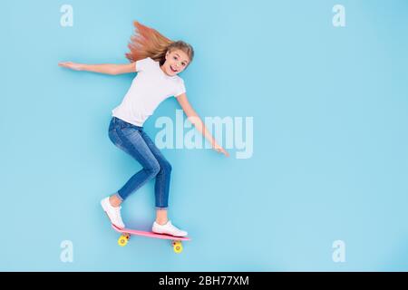 Top über hohen Winkel Ansicht Vollkörper Foto von energetischen aufgeregt verrückte Mädchen Kind fahren Skateboard kopieren Raum lag isoliert über blauen Hintergrund Stockfoto