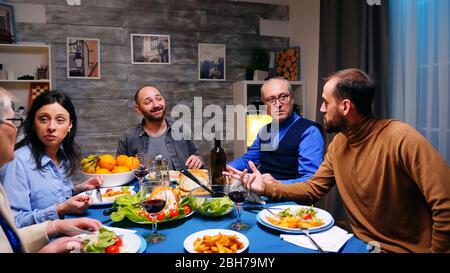 Zwei Söhne, die beim Abendessen mit ihrem Vater ein Gespräch führen. Leckeres Essen. Stockfoto