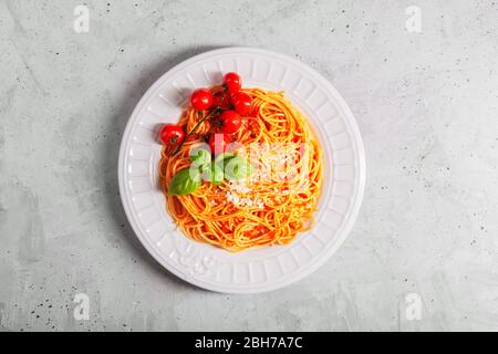 Pasta mit Tomatensauce und Kirschtomaten mit Basilikum auf weißem Hintergrund. Kopierbereich. Frische oder trockene Spaghetti werden in einem großen Topf mit gesalzenem gekocht Stockfoto