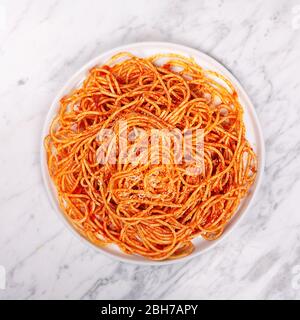 Pasta mit Tomatensauce und Kirschtomaten mit Basilikum auf weißem Hintergrund in einem modernen Teller Stockfoto