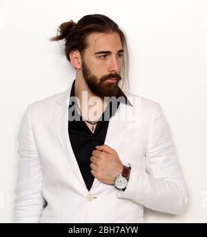 Junge, modische männliche Modell mit langen Haaren und Bart posiert im Studio auf isoliertem Hintergrund. Mode, Business, Modellierungskonzept. Stockfoto