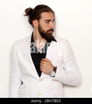 Junge, modische männliche Modell mit langen Haaren und Bart posiert im Studio auf isoliertem Hintergrund. Mode, Business, Modellierungskonzept. Stockfoto