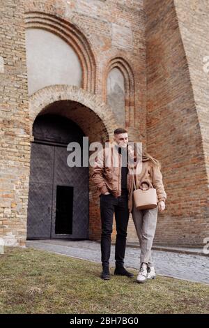 Junge glückliche Paar auf alten Stadthintergrund. Ein Liebespaar, das einen Spaziergang im Innenhof der Altstadt genießt. Vor dem Hintergrund rote Ziegelwände Stockfoto