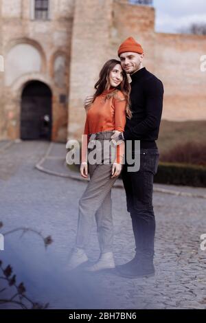 Junge glückliche Paar auf alten Stadthintergrund. Ein Liebespaar, das einen Spaziergang im Innenhof der Altstadt genießt. Vor dem Hintergrund rote Ziegelwände Stockfoto