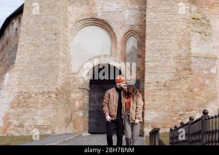 Junge glückliche Paar auf alten Stadthintergrund. Ein Liebespaar, das einen Spaziergang im Innenhof der Altstadt genießt. Vor dem Hintergrund rote Ziegelwände Stockfoto