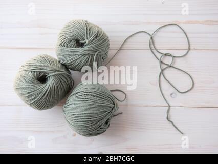 Strickfäden auf dunklem hellem Holzhintergrund. Stockfoto