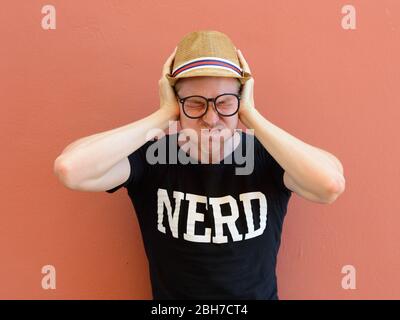 Porträt von gestressten jungen Nerd Tourist Mann Ohren bedeckt Stockfoto