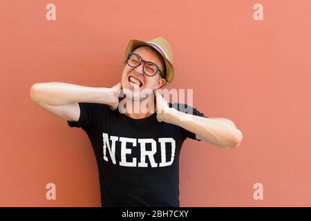 Porträt von gestressten jungen Nerd Tourist Mann mit Nackenschmerzen Stockfoto