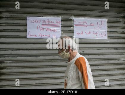 Beirut, Libanon. 24. April 2020. Ein Fußgänger, der eine schützende Gesichtsmask gegen Covid-19 trägt, geht am Gedenktag des armenischen Völkermordes an einem geschlossenen Laden vorbei. Die Türkei lehnt jede Verantwortung ab und hat immer bestritten, dass die Morde Völkermord waren. Kredit: amer Ghazzal/Alamy Live News Stockfoto