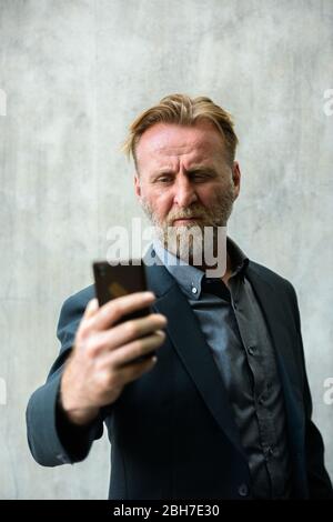 Reifen gut aussehend bärtigen Geschäftsmann mit Telefon im Freien Stockfoto