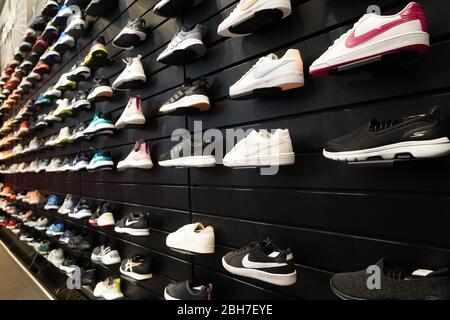 Zeigen Sie viele Sportschuhe an einer Wand an. Blick auf eine Wand aus Schuhen im Laden. Moderne neue, stilvolle Turnschuhe für Herren und Wom Stockfoto