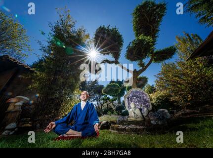 Der ehemalige buddhistische Mönch Buddha Maitreya, der sagt, dass die Pandemie eine Warnung an die Menschheit ist, meditiert in seinem preisgekrönten Japanischen Garten im Pure Land Meditationszentrum in der Nähe von Newton auf Trent. Stockfoto