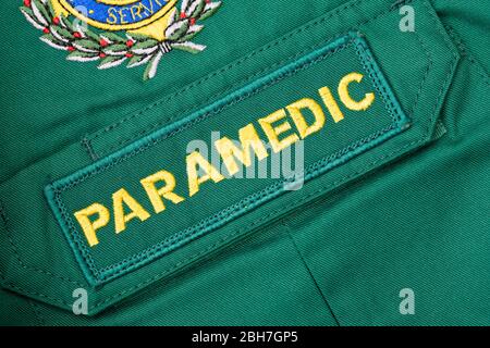 Nahaufnahme, schräge Ansicht eines britischen SANITÄTER-Abzeichen, das auf ein grünes Sanitäter-Hemd genäht ist. Stockfoto