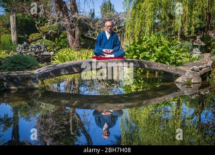 Der ehemalige buddhistische Mönch Buddha Maitreya, der sagt, dass die Pandemie eine Warnung an die Menschheit ist, meditiert in seinem preisgekrönten Japanischen Garten im Pure Land Meditationszentrum in der Nähe von Newton auf Trent. Stockfoto