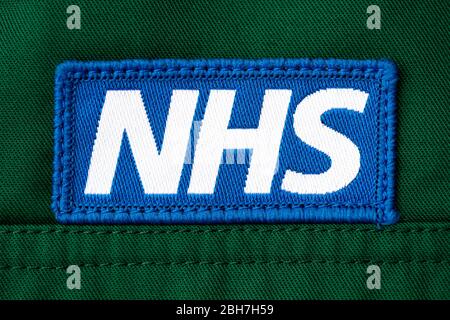 Nahaufnahme des Abzeichen des NHS (National Health Service), das auf die Uniform eines britischen Sanitäter-Trikots aufgenäht ist. Stockfoto