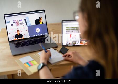 24. April 2020, Bayern, München: ILLUSTRATION - EINE Frau nimmt sich bei einer Online-Pressekonferenz nach einer Mitgliederversammlung der Deutschen Fußball-Liga zu den Folgen der Corona-Pandemie Notizen. Auf dem Monitor des Laptops sind Tim Meyer (von oben links nach unten rechts), Leiter der Task Force Sportmedizin/Special Game Operations des DFL und Ärztliche Direktorin des Instituts für Sport und Präventivmedizin der Universität des Saarlandes, Barbara Gärtner, zu sehen. Mitglied der Task Force Sportmedizin/Special Game Operations des DFL sowie Leiter der Krankenhaushygiene am Institut für Medi Stockfoto