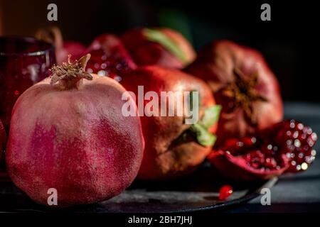 Granatapfelfrucht. Granatäpfel über dunklem Hintergrund. Bio-Früchte mit Blättern und Samen Stockfoto