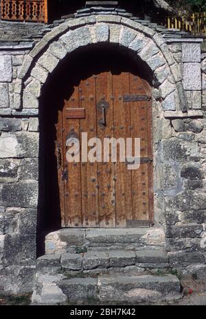 Alte braune, hölzerne, Tür mit kunstvollen, antiken, handgefertigten Beschlägen, gesetzt in einer Steinmauer in Metsovo, Ioannina, Epirus, Griechenland Stockfoto