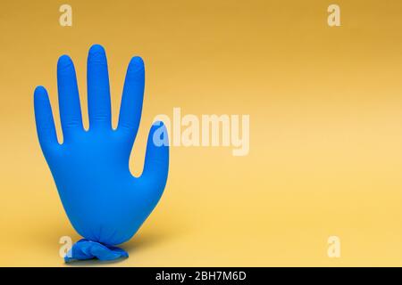 Blauer medizinischer Handschuh aufgeblasen. Auf gelbem Hintergrund mit Kopierbereich. Stockfoto