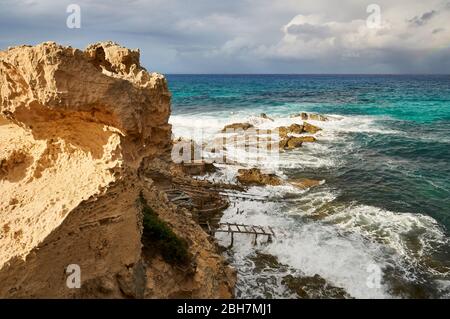 Traditionelle Bootshäuser, die als ewagen bezeichnet werden, in Es Carnatge Küste mit blauem rauem Wasser (Formentera, Pityuses, Balearen, Mittelmeer, Spanien) Stockfoto