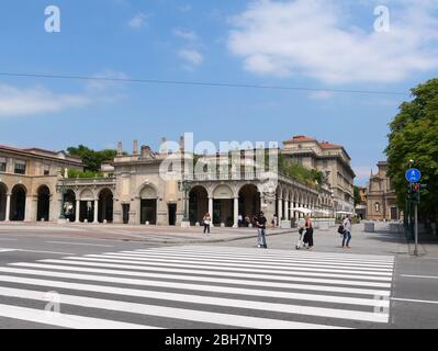 Bergamo, Italien - 06. August 2019: Personen mit Elektroscootern warten auf die Kreuzung vor Santi Bartolomeo e Stefano, eine barocke römische Katze Stockfoto