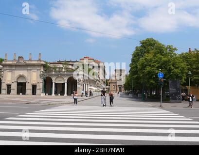 Bergamo, Italien - 06. August 2019: Personen mit Elektroscootern warten auf die Kreuzung vor Santi Bartolomeo e Stefano, eine barocke römische Katze Stockfoto